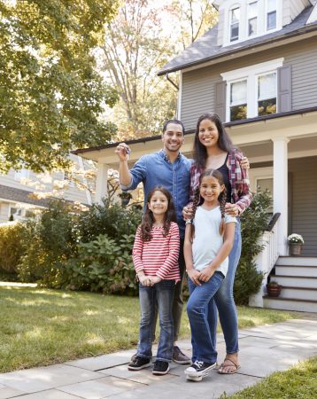 Portrait Of Family Holding Keys To New Home On Moving In Day