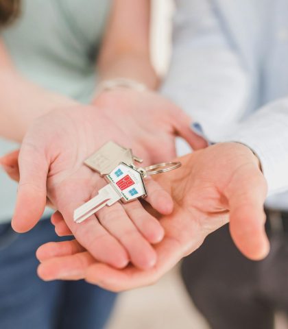 Close-up of a couple holding keys, symbolizing homeownership and investment.